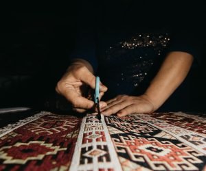 Cutting ethnic carpet with scissors. High quality photo